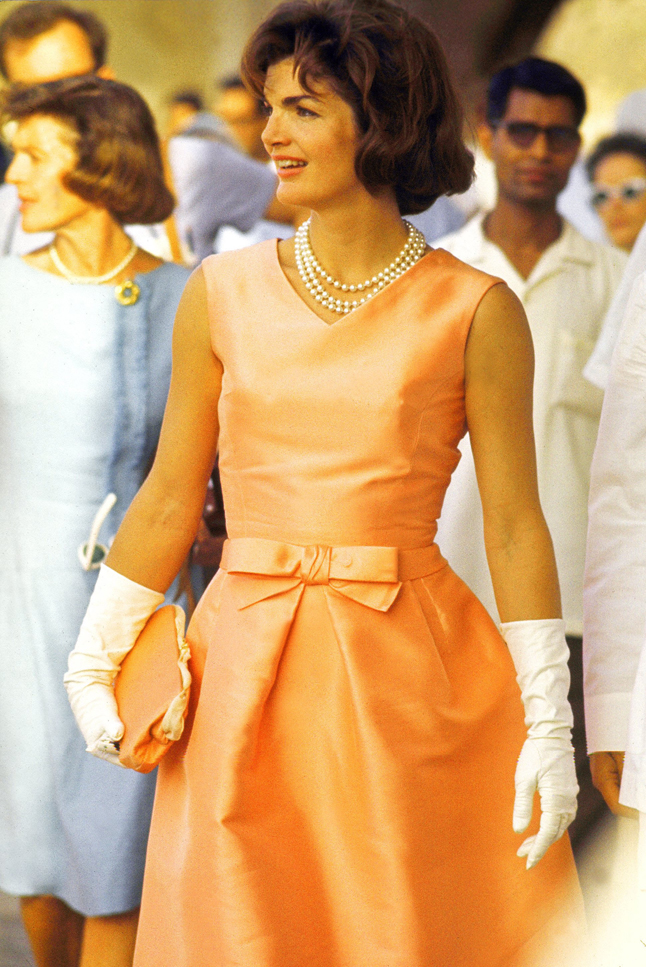 First Lady Jackie Kennedy wearing a fitted silk apricot dress and triple strand of pearls, walking through crowds at Udaipur during visit to India.  (Photo by Art Rickerby//Time Life Pictures/Getty Images)